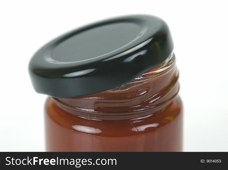 A small jar of ketchup isolated against a white background