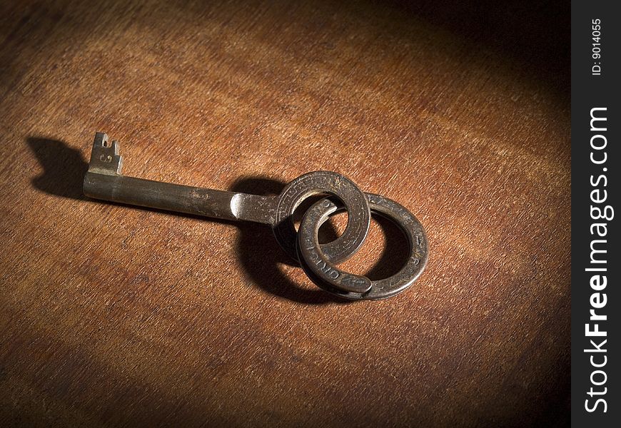 An old key on a keyring over a wooden table.