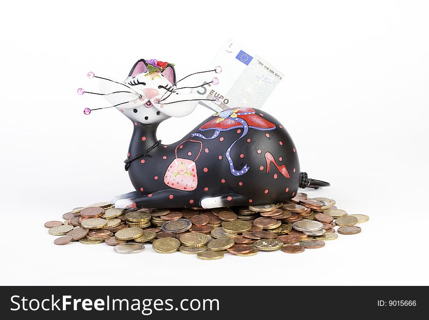 Piggybank (cat) sitting on euro coins with banknote on back