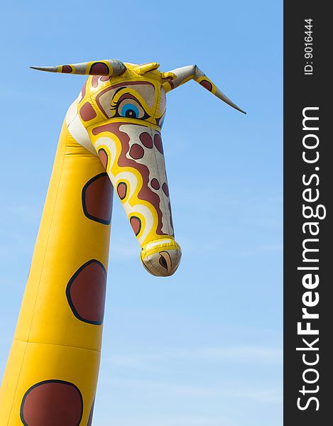 An looking rubber giraffe against an blue sky