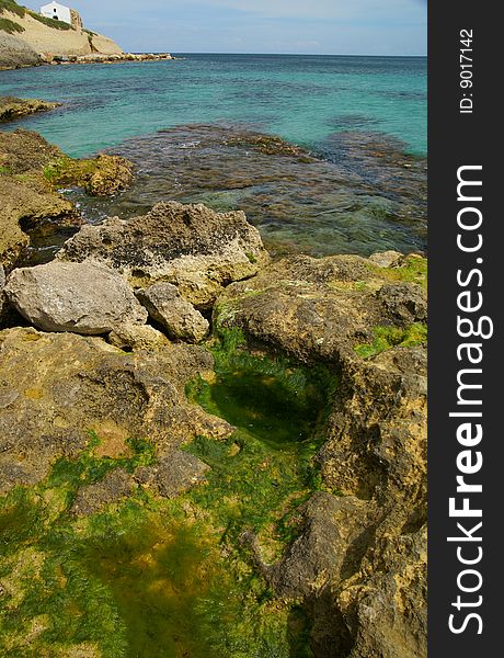 A shoot of rock in the sea of Portotorres - Sardinia - And a white church. A shoot of rock in the sea of Portotorres - Sardinia - And a white church.