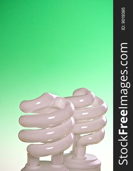 Two compact fluorescent lightbulbs with a green background. Two compact fluorescent lightbulbs with a green background