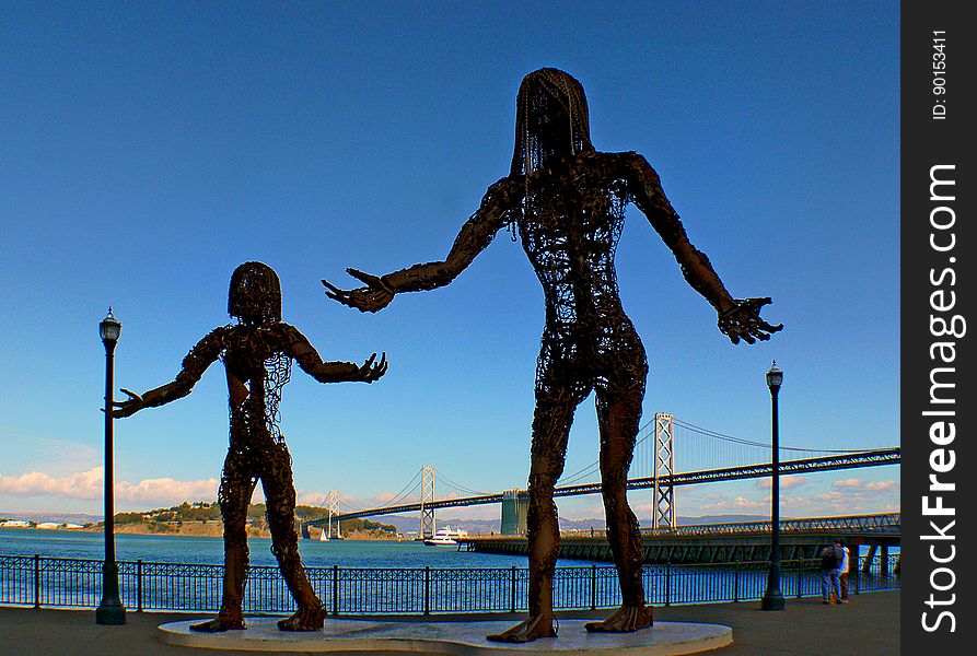 Gracing the waterfront of downtown San Francisco, this amazing display looks to be depicting a mother and daughter, with the much larger mother pouring something from her hand into the outstretched hand of her little girl. The statues have been constructed of metal, with both constructs composed of mostly empty air. While the family portrait is beautiful, the starkness of the metal and the cruelly formed hands give the display an almost dark and eerie look, depending on how you want to interpret the scene!. Gracing the waterfront of downtown San Francisco, this amazing display looks to be depicting a mother and daughter, with the much larger mother pouring something from her hand into the outstretched hand of her little girl. The statues have been constructed of metal, with both constructs composed of mostly empty air. While the family portrait is beautiful, the starkness of the metal and the cruelly formed hands give the display an almost dark and eerie look, depending on how you want to interpret the scene!