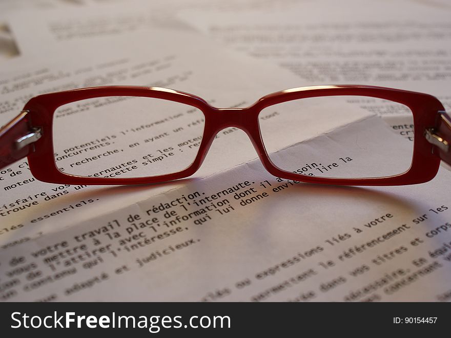 Red Framed Eyeglass on Top of Paper