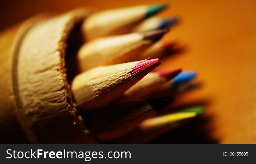 Close up of colored pencil tips in wooden cup. Close up of colored pencil tips in wooden cup.