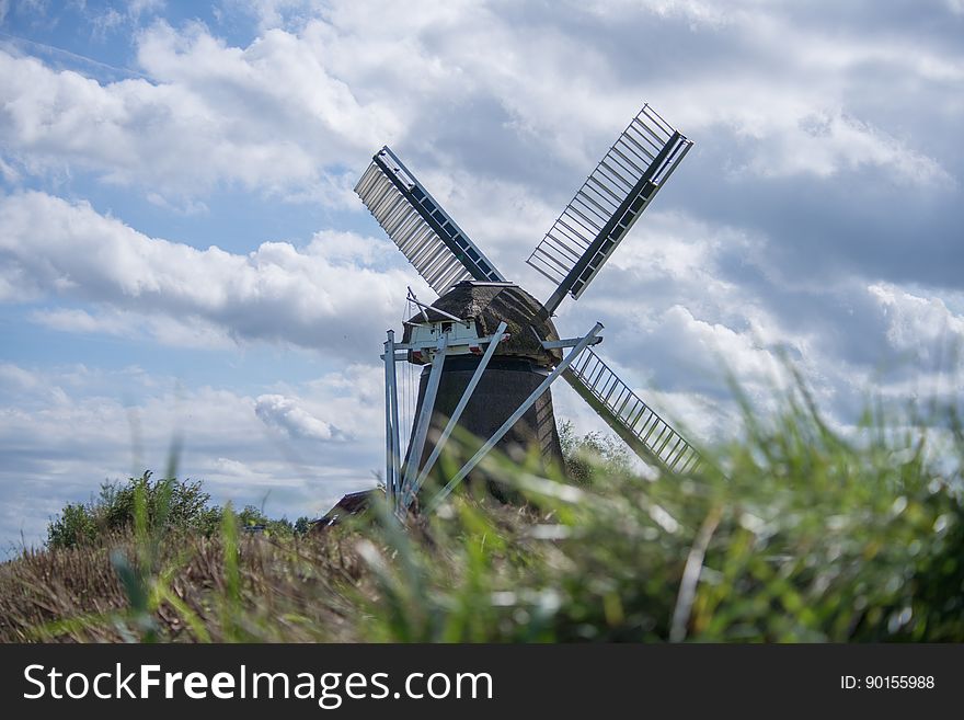 Windmill in grassy field against blue skies with clouds, Netherlands. Windmill in grassy field against blue skies with clouds, Netherlands.