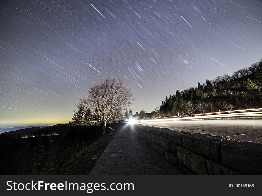 Star trails over country roadway along coastline at sunset. Star trails over country roadway along coastline at sunset.