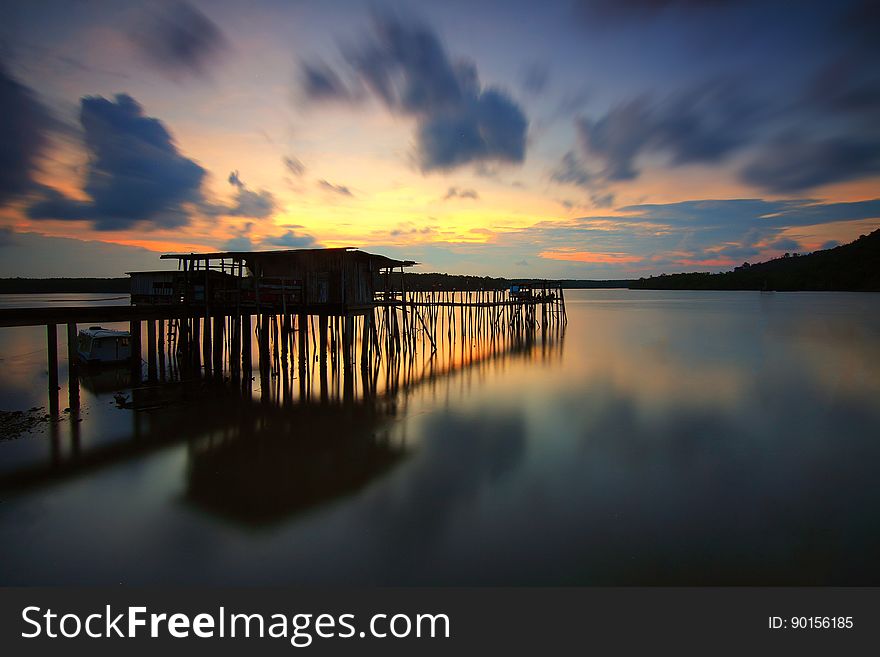 A house on stilts on the seashore at dusk.