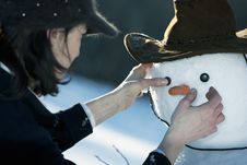 Woman Decorating A Snowman Royalty Free Stock Photos