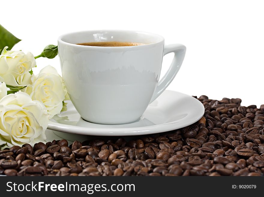 A cup of coffee with white roses and coffee beans isolated on white background. A cup of coffee with white roses and coffee beans isolated on white background