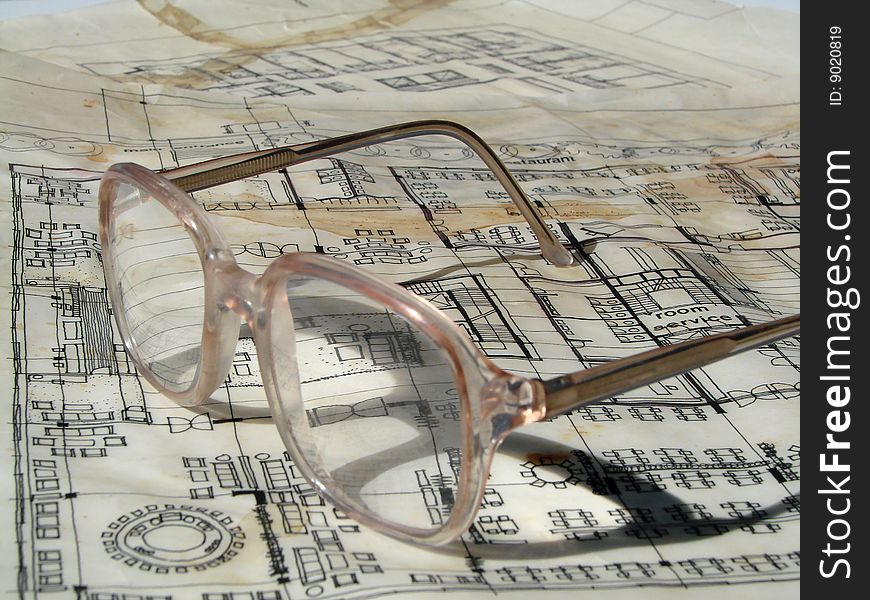 Old architectural construction document with old-fashioned glasses on it. Old architectural construction document with old-fashioned glasses on it.