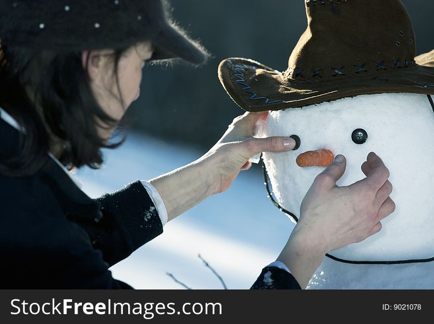 Beautiful woman decorating a snowman