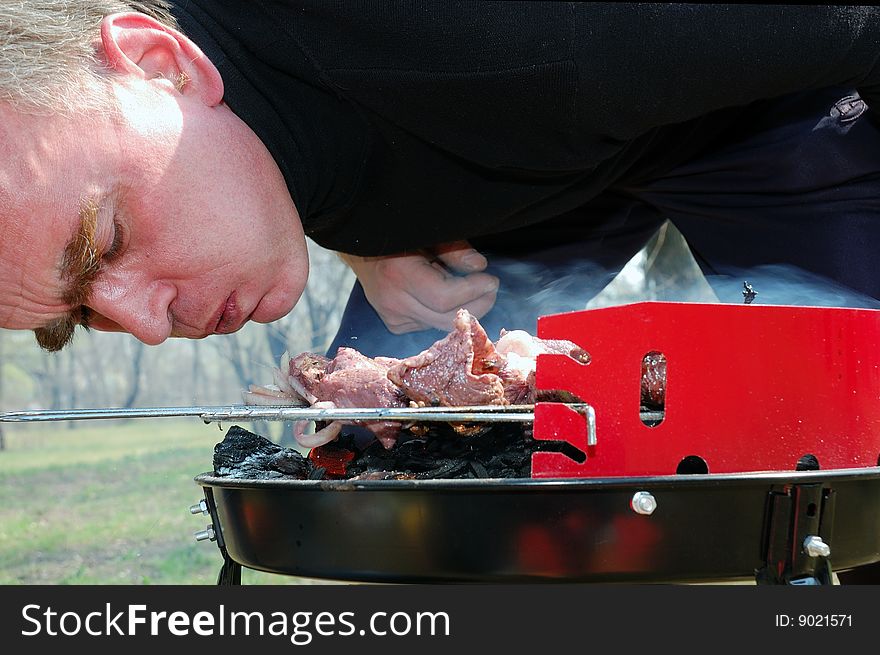 Middle aged man blowing up the barbecue fire