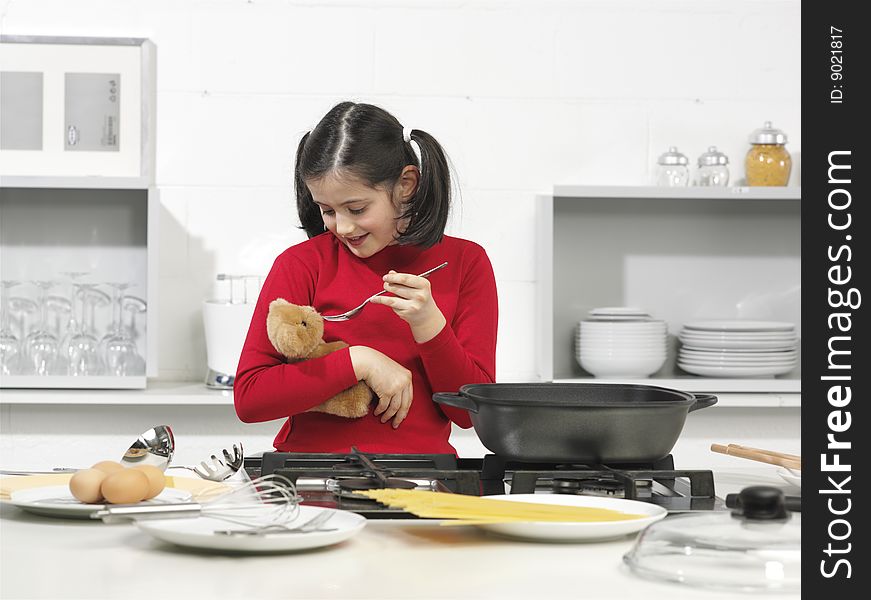 Little girl in the kitchen with his bear