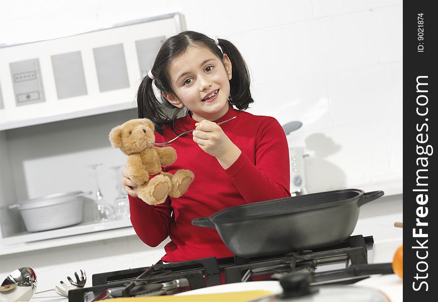 Little girl in the kitchen with his bear