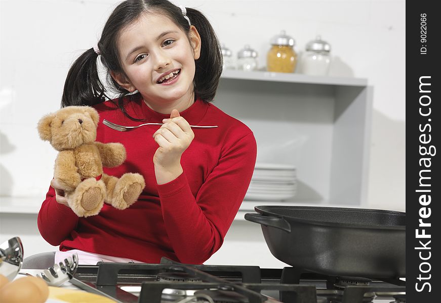 Little girl in the kitchen with his bear