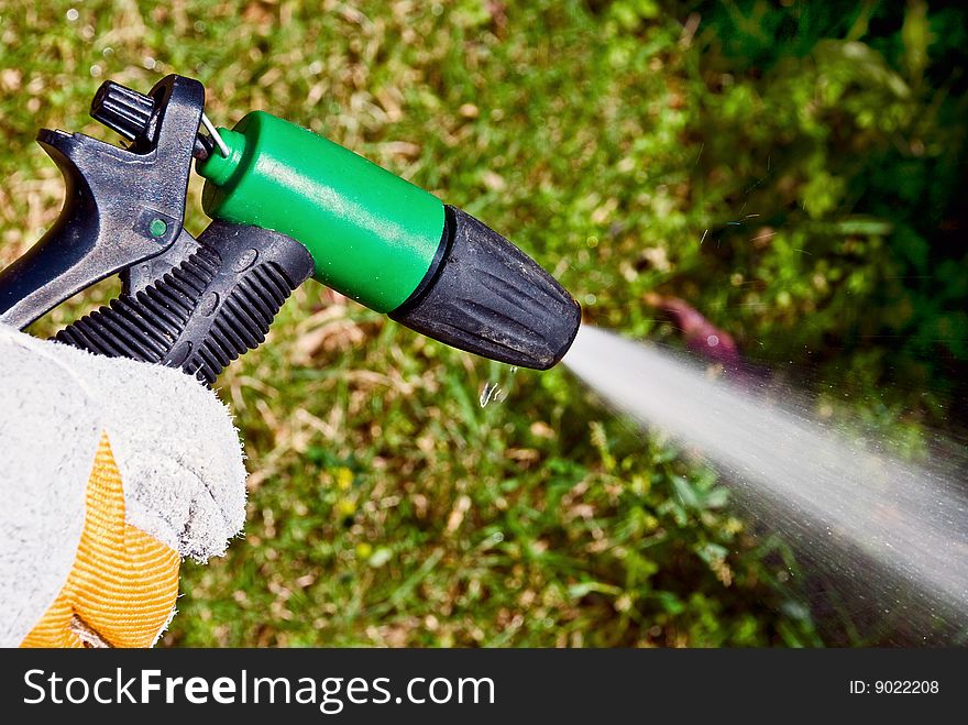 A man's hand keeping a spouting sprinkler at the garden. A man's hand keeping a spouting sprinkler at the garden.