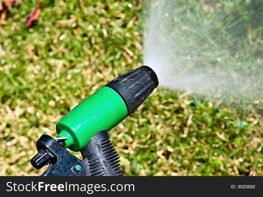Spouting sprinkler against the green grass background