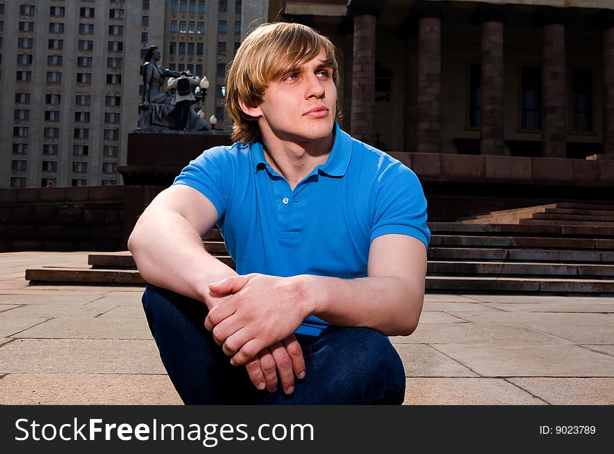 Cool young blond man sitting outdoors