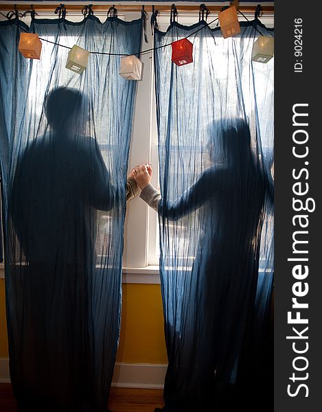 Young couple holding hands behind blue curtains. Young couple holding hands behind blue curtains.