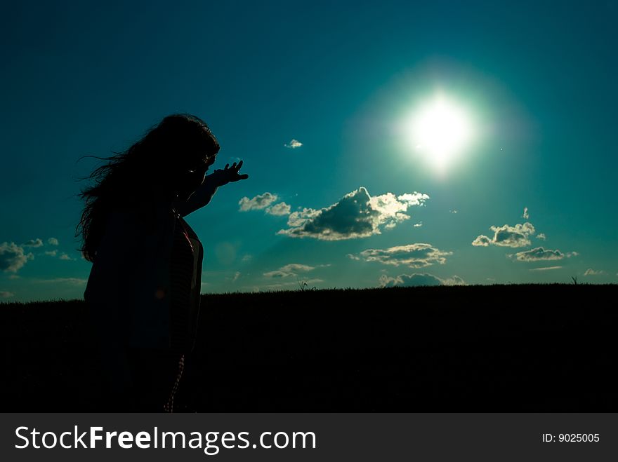 Silhouette of a girl reaching out to the sun