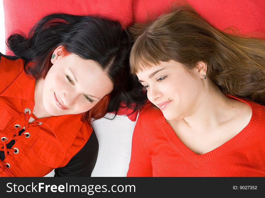 Two beautiful girls lying on red pillows. Two beautiful girls lying on red pillows