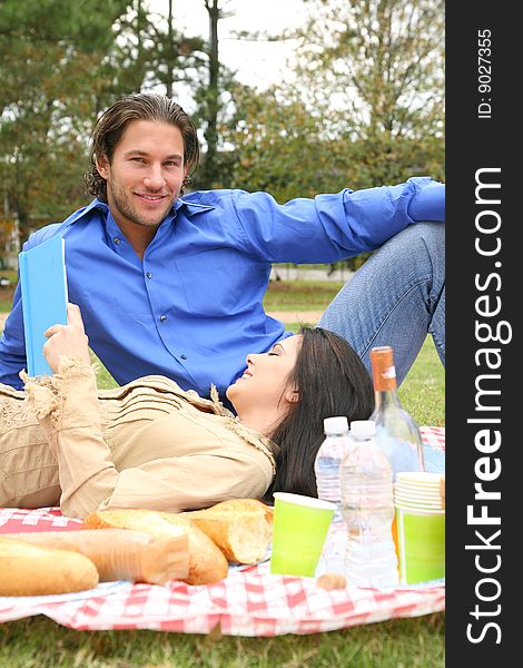 Young couple enjoying picnic on summer day. the man is looking at camera. Young couple enjoying picnic on summer day. the man is looking at camera