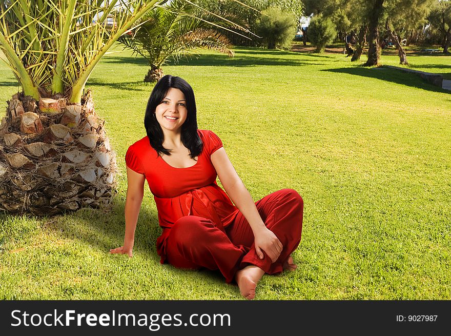 Young Pregnant woman sitting on the grass