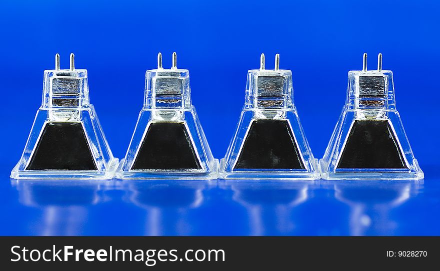 Four atypical square halogen light bulbs standing in a row and isolated on intensive blue background. Four atypical square halogen light bulbs standing in a row and isolated on intensive blue background