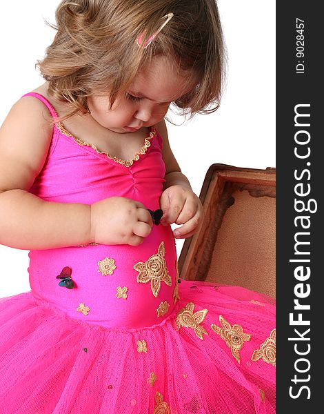 Little girl with wearing a bright pink tutu standing in an old suitcase