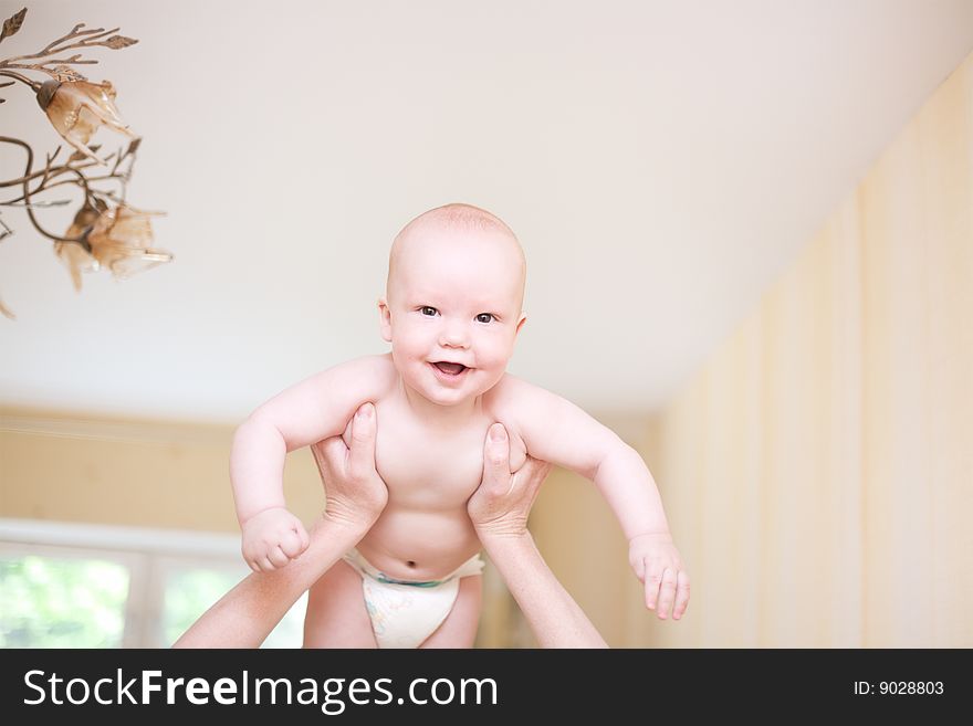 Mother holding enjoying baby in hands at living room