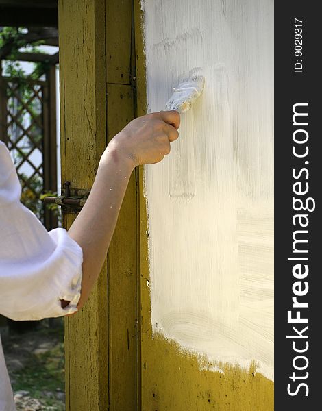 Woman painting the door with white color
