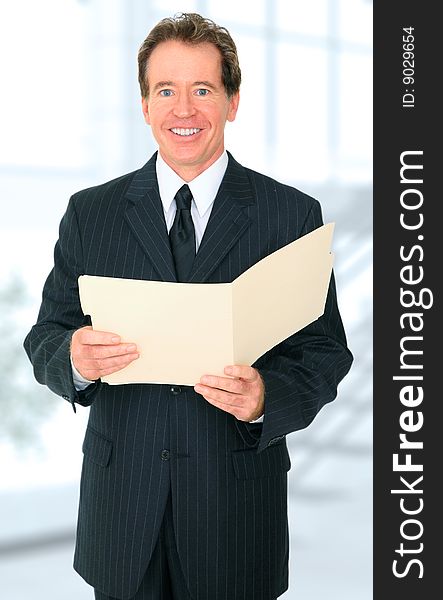 Caucasian senior businessman holding up folder but look to viewer with happy expression. Caucasian senior businessman holding up folder but look to viewer with happy expression