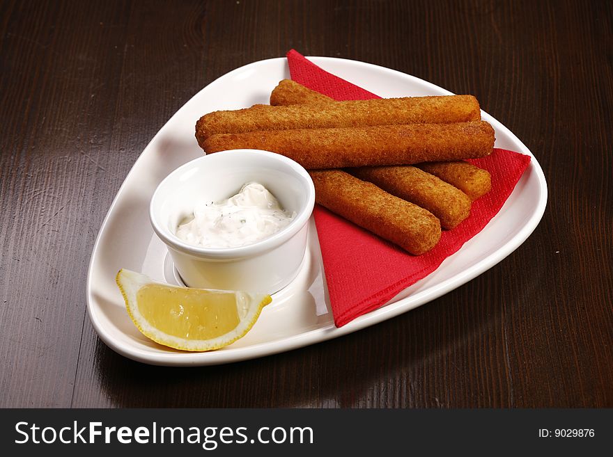 Roasted cheese sticks on white plate on brown table with clipping path