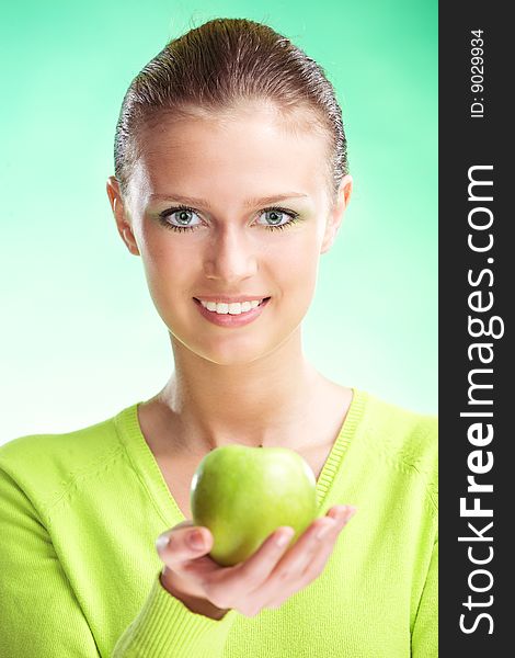 Young beauty woman with apple on green background