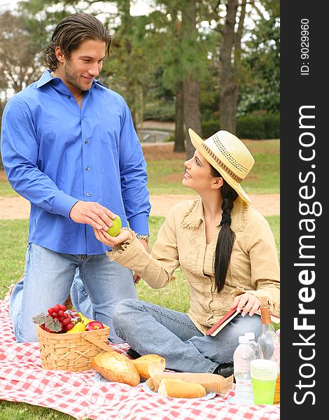 A girl offer fruit to her boyfriend in picnic summer day outdoor. A girl offer fruit to her boyfriend in picnic summer day outdoor