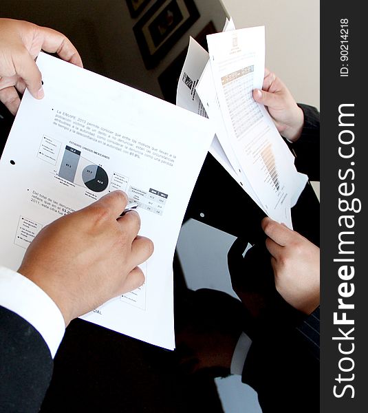 Close up of hands of business professionals holding documents with charts and information. Close up of hands of business professionals holding documents with charts and information.