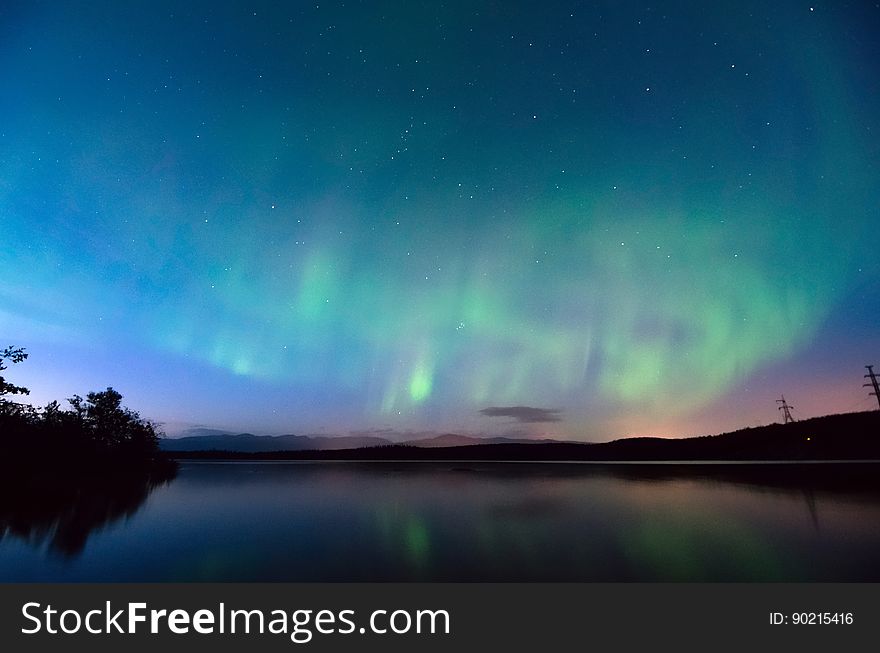 A view of a lake at night with the aurora on the sky. A view of a lake at night with the aurora on the sky.