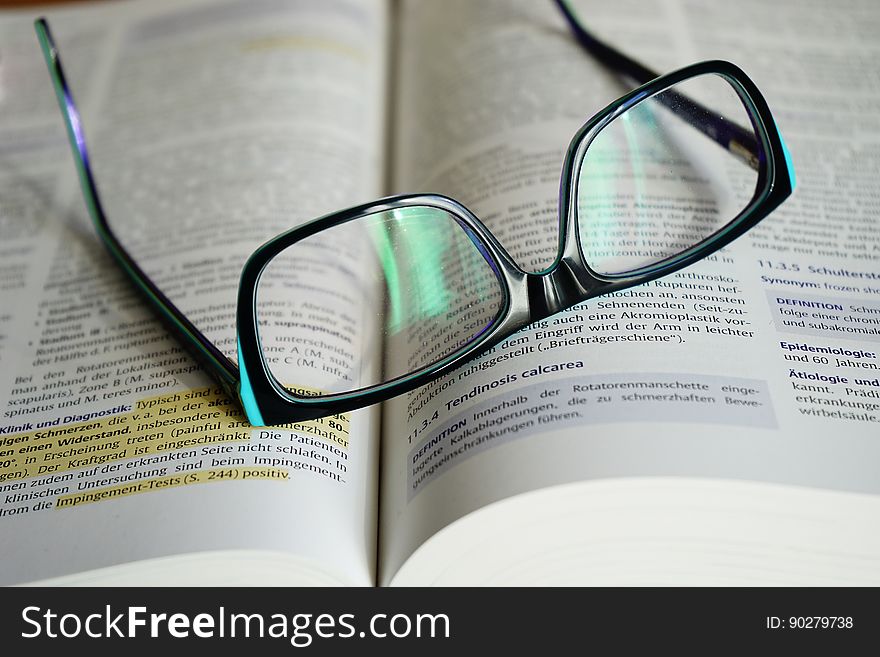 Close up of black frame glasses on open book with highlighter. Close up of black frame glasses on open book with highlighter.