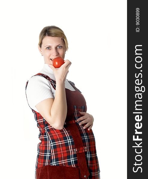 The pregnant girl holds a red tomato in a hand