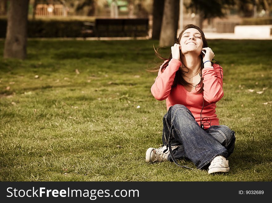 Young beauty listening music on the grass