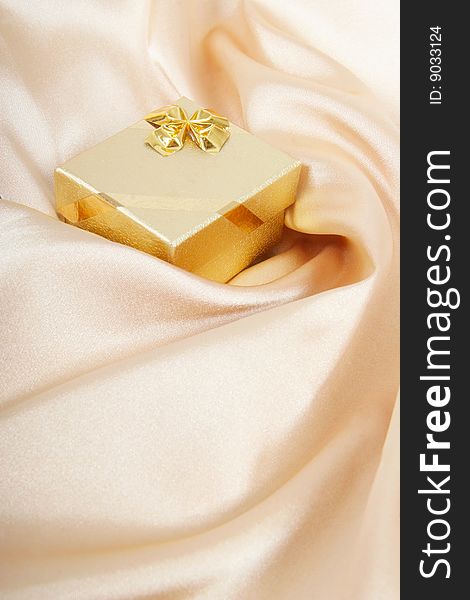 Golden gift box on silk background. Golden gift box on silk background