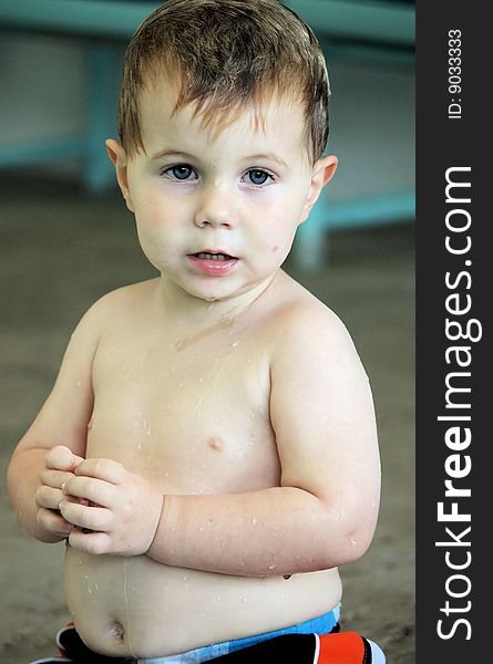 Little boy sitting on the side of the pool wet from swimming. Little boy sitting on the side of the pool wet from swimming