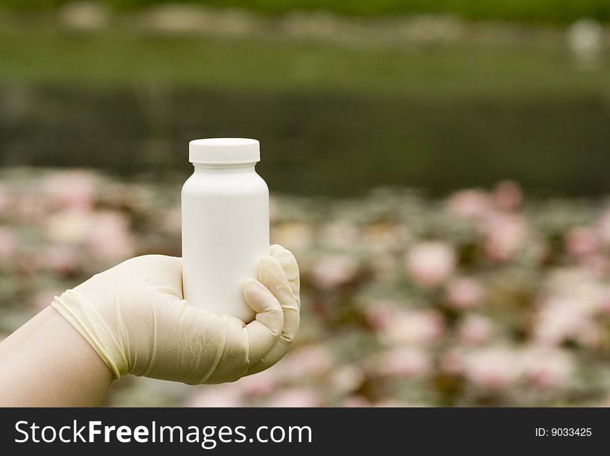 A white box in hand. The white surface waiting for your product label. Water lily in the background.