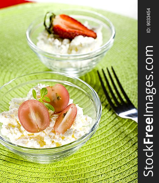 Cottage cheese with grapes and strawberry on a color cover
