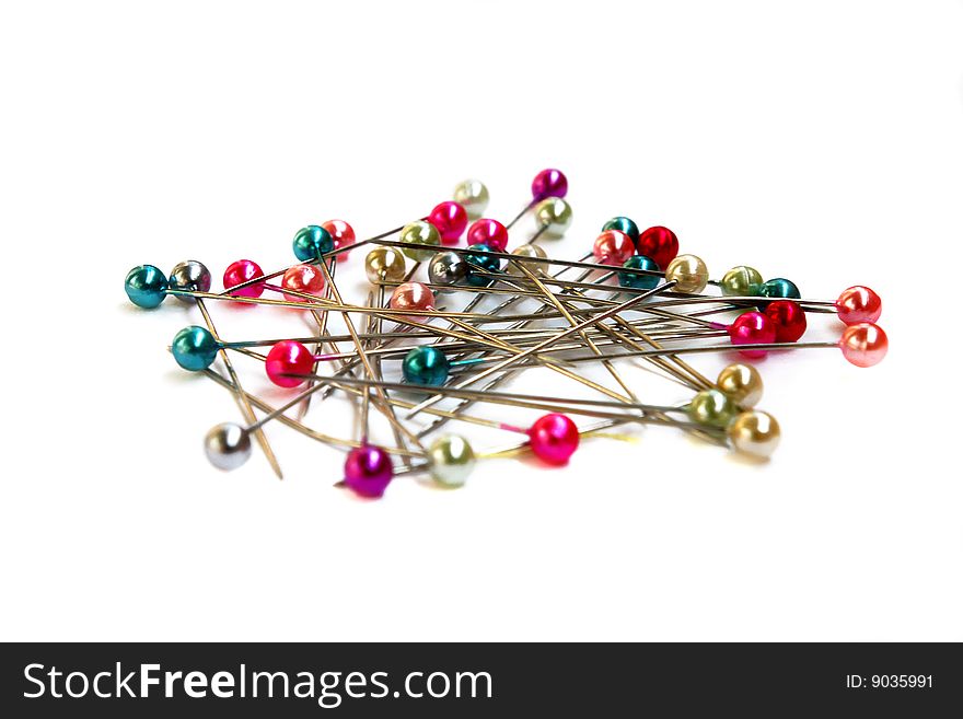 Heap of multi-coloured sewing pins on a white background