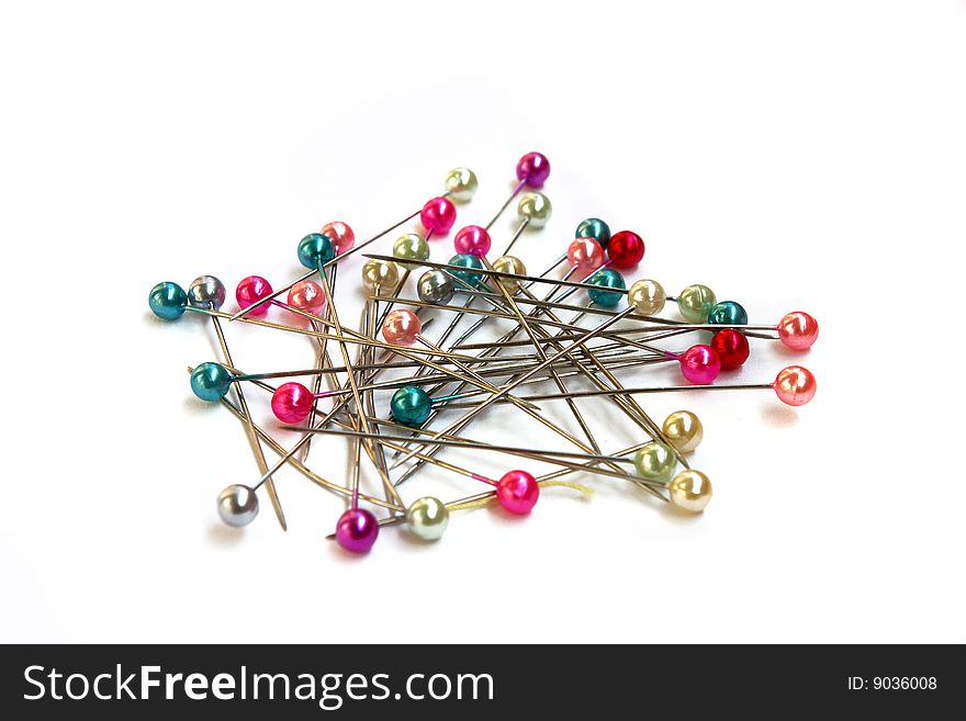 Heap of multi-coloured sewing pins on a white background