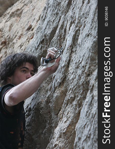 Climber clipping quick-draw on limestone rock