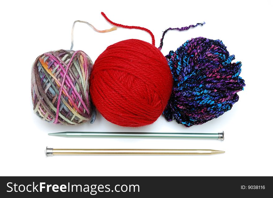 3 colorful balls of yarn above 2 metal knitting needles. 3 colorful balls of yarn above 2 metal knitting needles