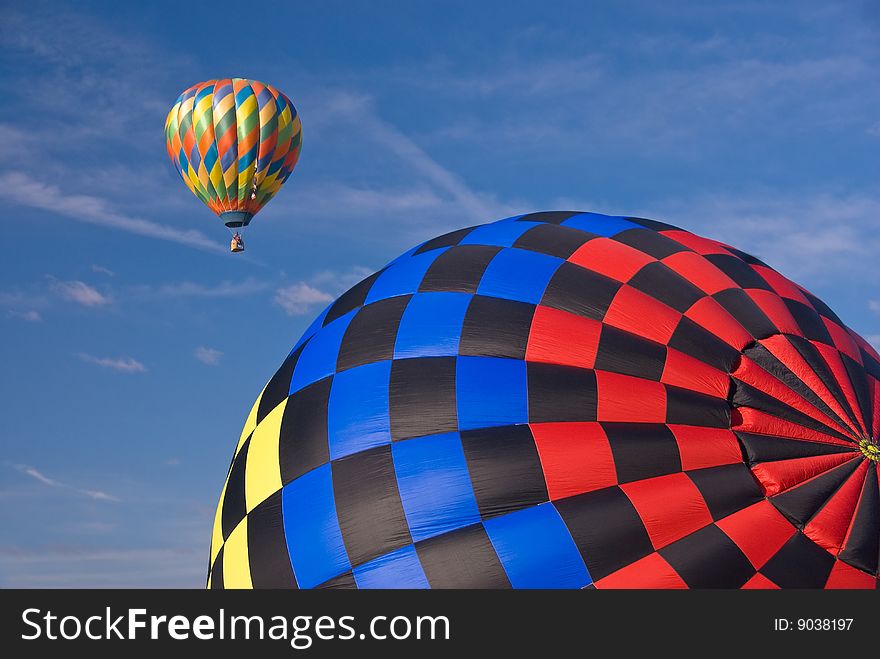 Two hot air balloons with a blue sky background
